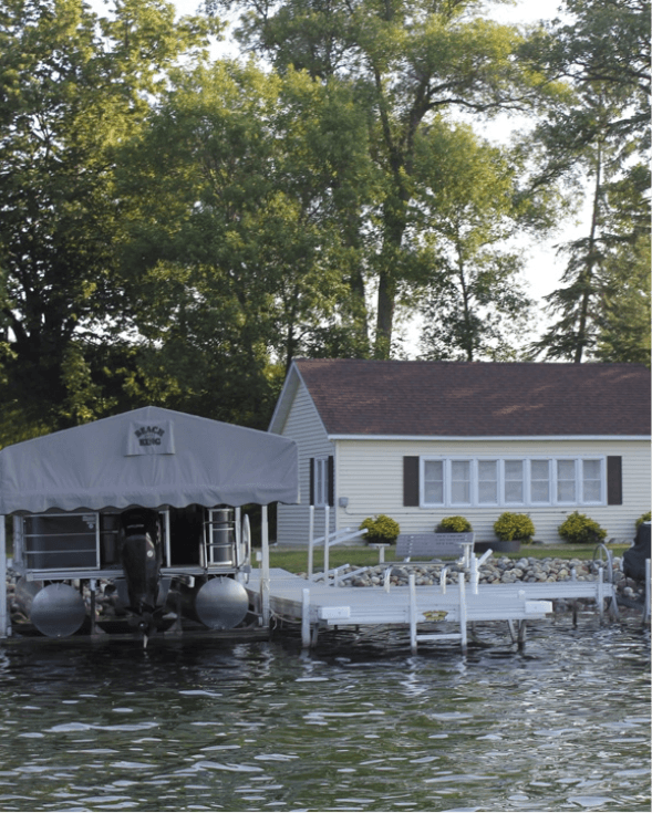 Lakefront cottage with boat dock, surrounded by trees and a serene water view.