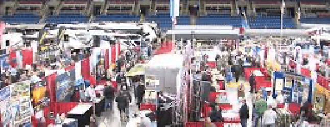 Busy trade show with colorful booths and numerous attendees in a large indoor venue.