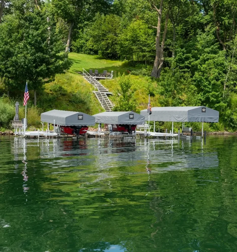 Three boat lifts on a serene lake surrounded by greenery