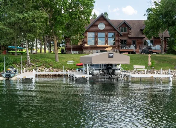 Dock and boat lift at a lakeside home with trees