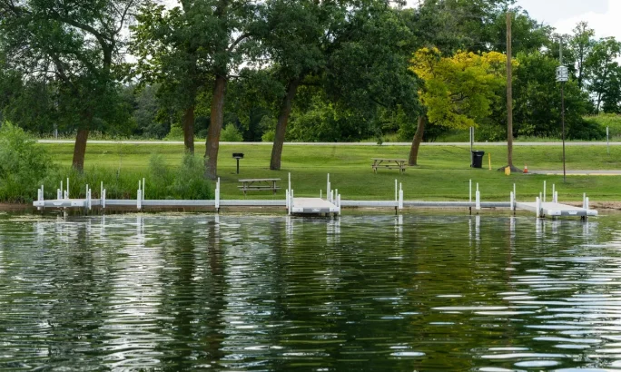Dock system on a calm lake surrounded by trees and grass.